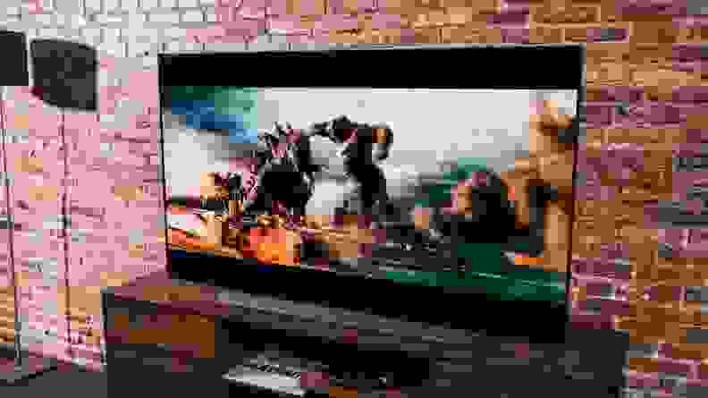 An LG TV showing a still from Godzilla vs. Kong against a brick wall.