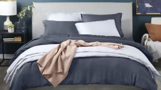The Casper hyperlite sheets in a dark gray on a made bed