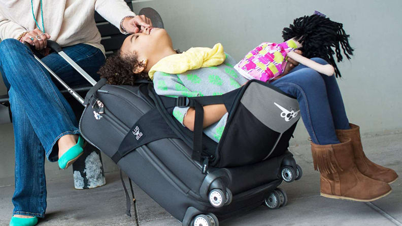 A girl sitting in a seat attached to a suitcase