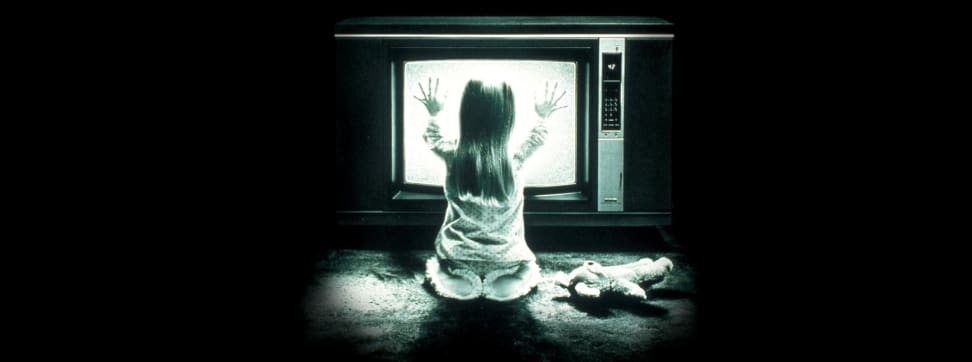 An image from the film Poltergeist showing a girl pressing her hands against a static TV.