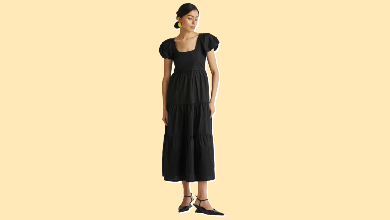 Photo of a woman wearing the Reistor Puff Sleeve Tiered Dress in black.