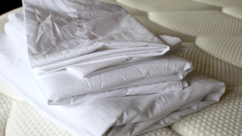 Sferra percale sheets, our top-performing sheets, folded and stacked on a mattress.