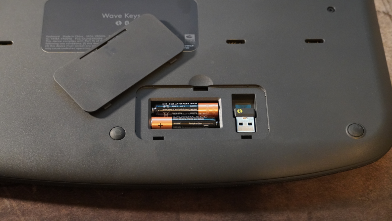 Close-up of the keyboard's AAA batteries and USB dongle slot.