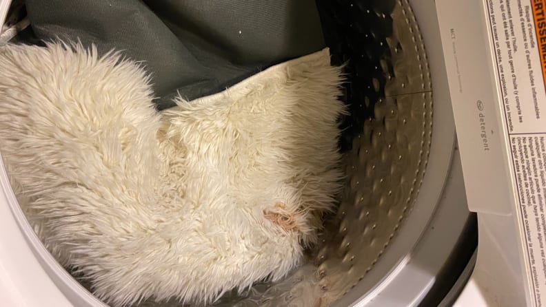Stained white shag rug in drum of washer machine.