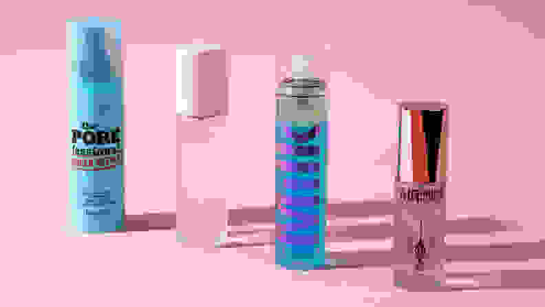 Four bottles of makeup setting spray on a pink background.
