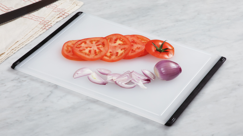 Plastic cutting board with sliced tomatoes and shallots on top