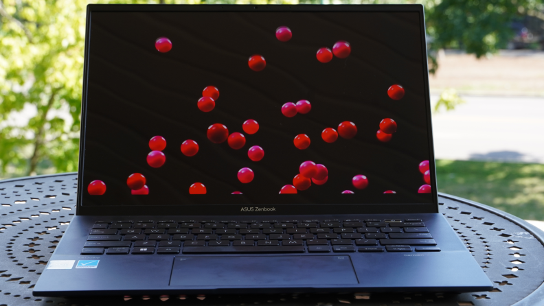 An open laptop sits on a patio table outside.