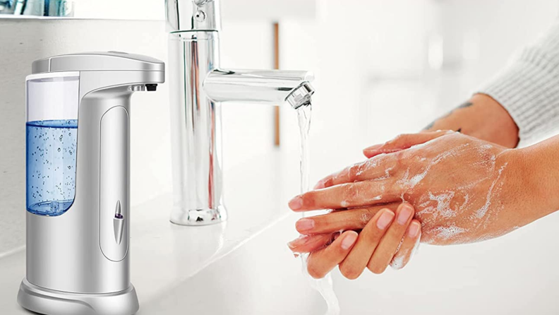 一个人用自动肥皂分配器洗手。