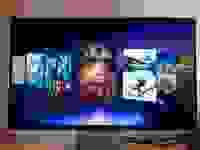 A 3D gaming monitor sits on a desk with video games gallery on its screen