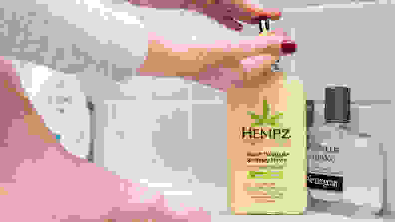 A person's hand pumping a bottle of body lotion.