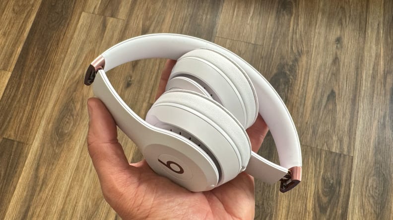 A hand holding the Beats Solo 4 headphones folded up.