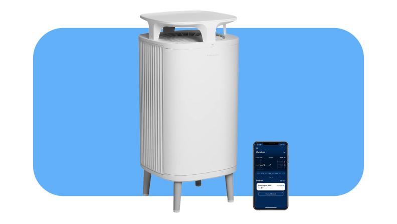 White BlueAir Dustmagnet 5410i air purifier next to smart phone with the Blueair app on screen.