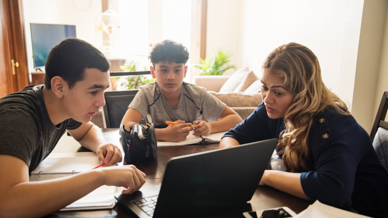 Family with one mom and two sons discussing with a laptop.