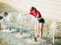 Two children playing in the water during a hot summer day.