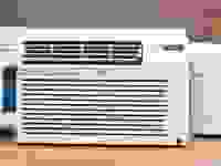 Three white air conditioning units are displayed on a wooden countertop