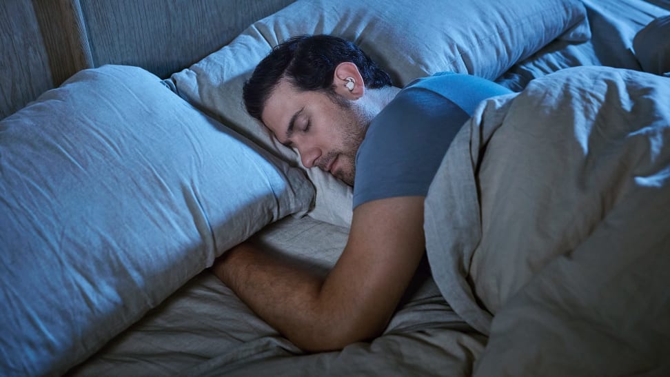 A man sleeps on one side revealing he's using the Bose Sleepbuds II.