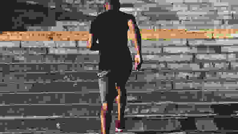 Rear view of young African man in sports clothing running up the stairs while exercising outdoors