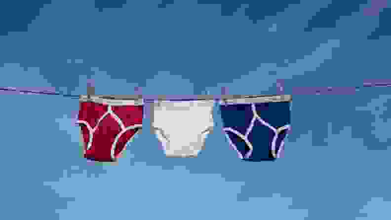 Three boxer briefs hanging up to line dry in front of a clear blue sky.