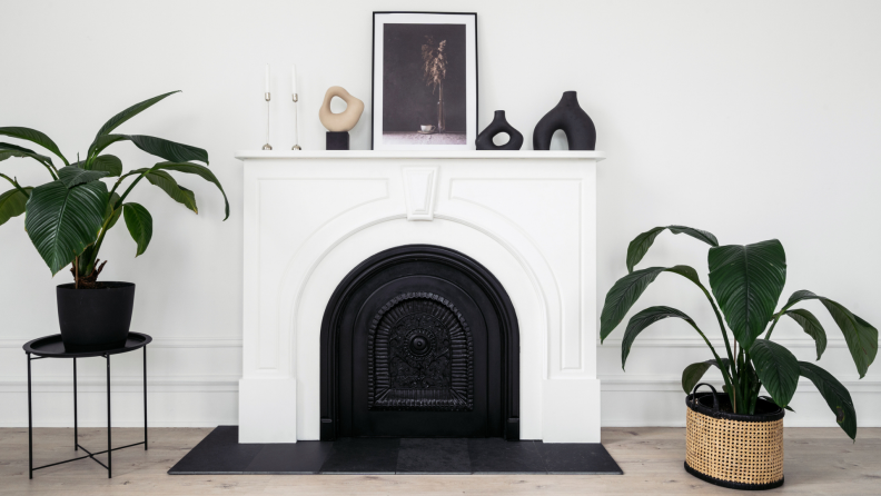 Small items surround a large frame on a mantel.