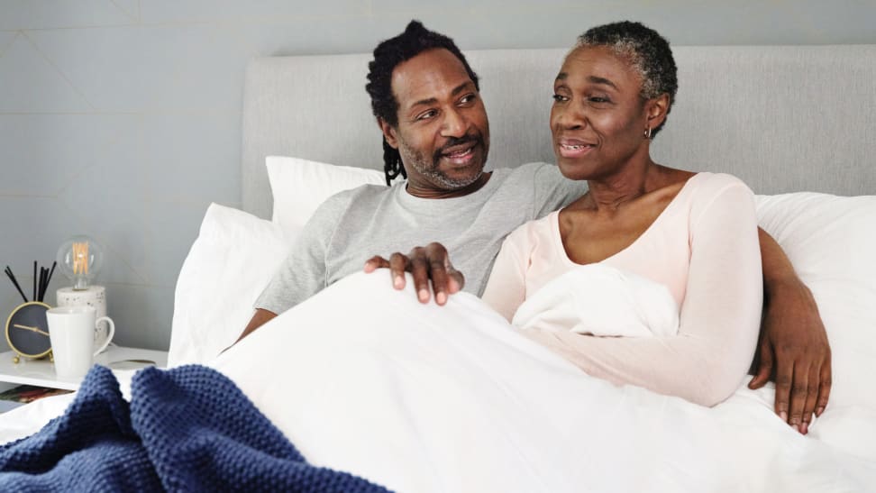 A couple lounges in bed together.