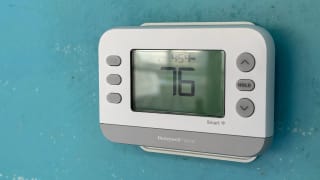 A smart thermostat on an aqua blue wall