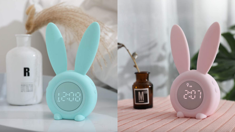 Bunny ear alarm clocks on pink blanket.