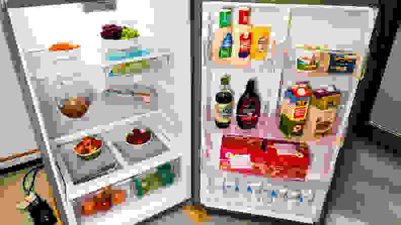 A shot of the Whirlpool WRT518SZFM top-freezer fridge  with its fridge compartment open, filled with food for scale.