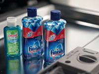 Bottles of rinse aid on an open dishwasher door.