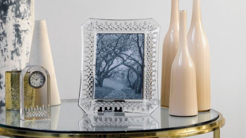 Crystal picture frame on glass end table next to vases and glass clock