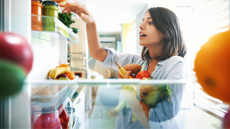 A person looking through the items in their refrigerator.