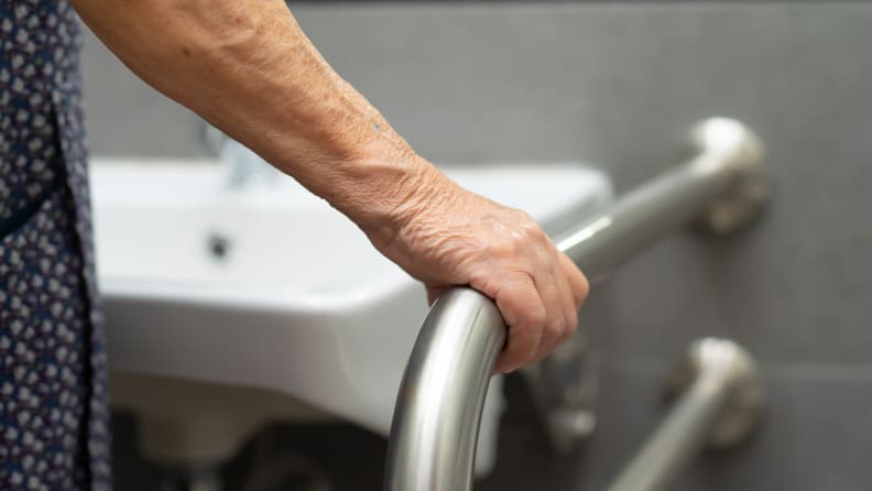 Hand gripping railing in bathroom