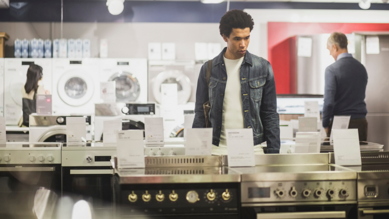 A man looks at laundry appliances while standing in a store