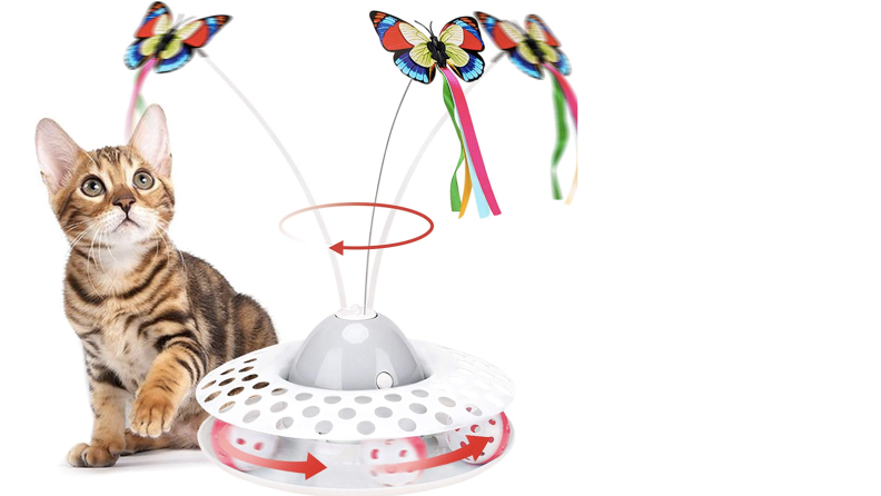 A cat plays with a floor toy featuring a motorized wand with a butterfly charm attached to the end