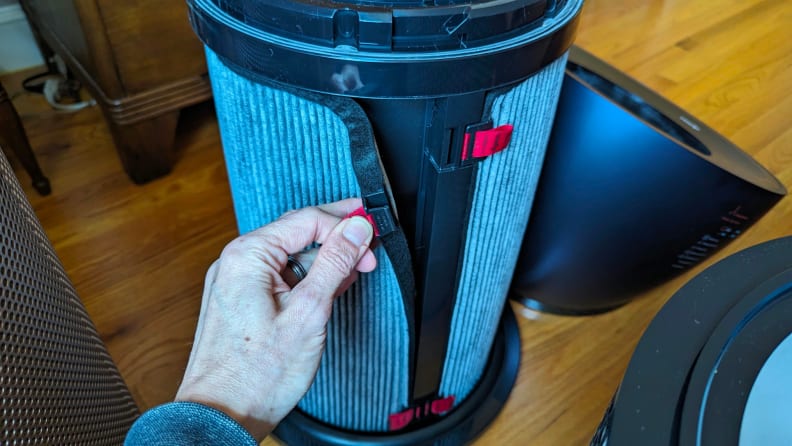 A hand pulls at a strap on the Dyson air purifier’s HEPA filter.