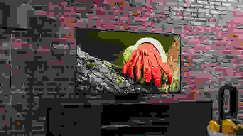 A bright red crab sits on a log on the TV's screen