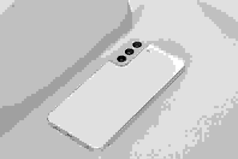 A white Galaxy S22+ lying against a grey background.