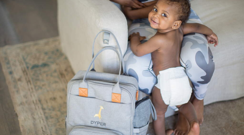 A baby stands in a Dyper diaper.