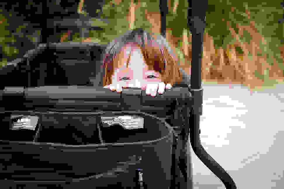 A child peeks over the top of a stroller wagon.