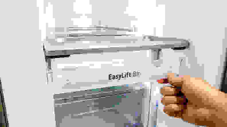 A close-up of a hand lifting up the edge of the "EasyLift bin" in the LG LRMVS3006S french door refrigerator