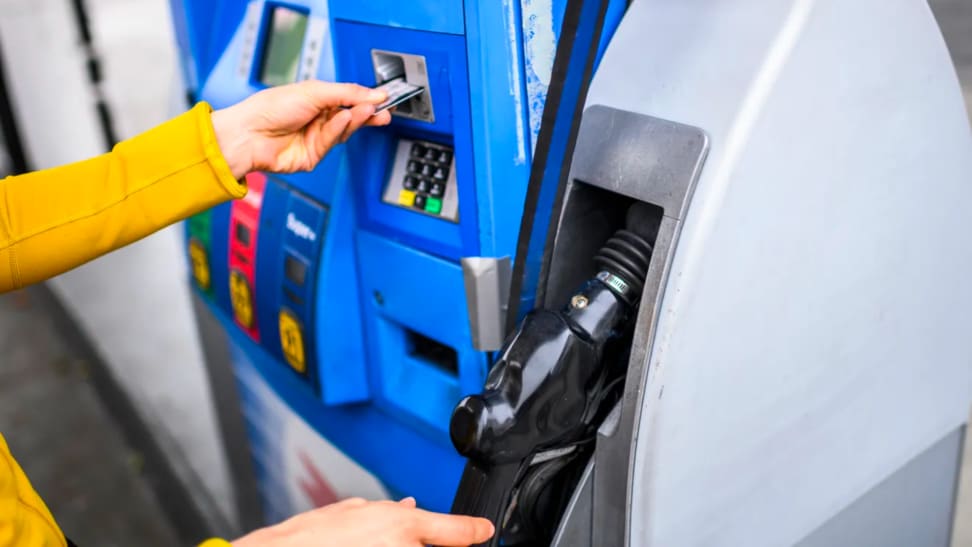 A person inserts their bank card into a gas pump.
