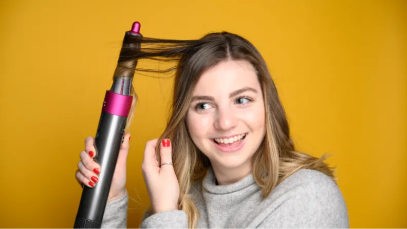 An image of a woman curling her hair around the Dyson Air Wrap.