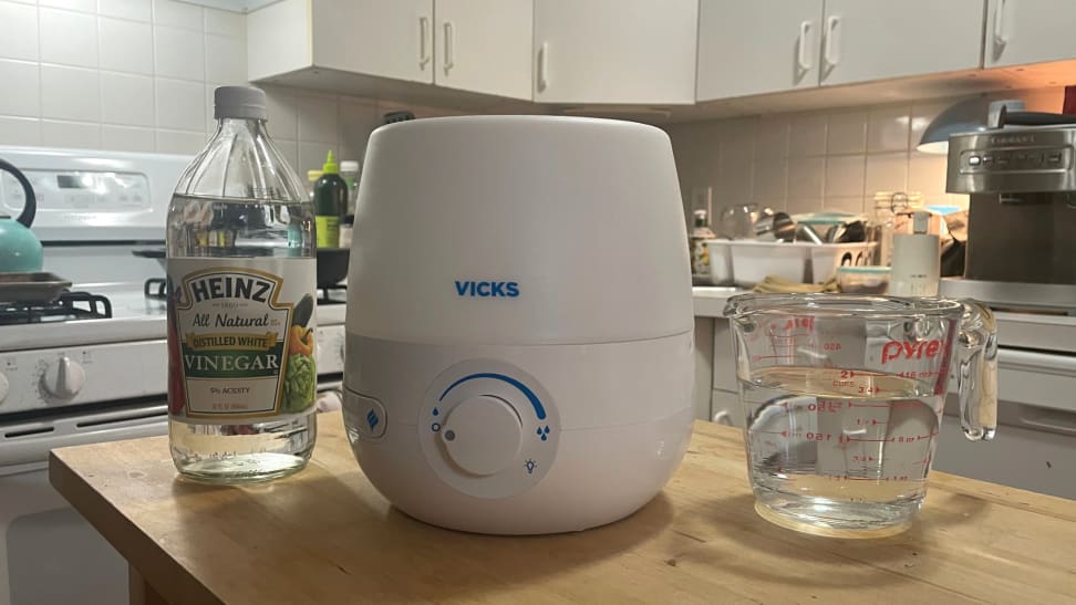 A humidifier with a bottle of white vinegar and water pitcher.