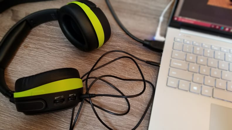 A pair of black headphones (with green-yellow accents) is plugged into a laptop.