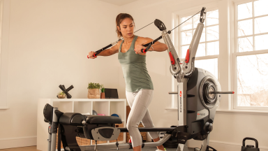 Photo of an athlete working out on a Bowflex machine at home.
