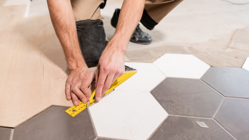 A worker measures new wood laminate flooring.