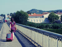 A woman walks down the road with a suitcase