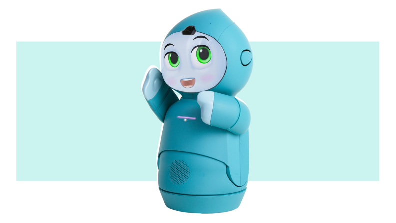 A light blue Moxie robotic companion standing upright with bright green eyes and an open-mouth smile.