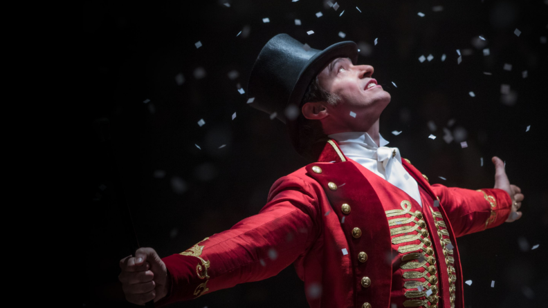 A still from 'The Greatest Showman' featuring Hugh Jackman standing in the middle of a group of performers.