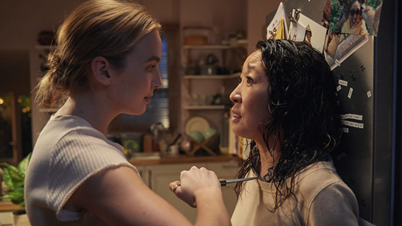 A still from Killing Eve where Villanelle (Jodie Comer) threatens Eve (Sandra Oh) with a knife in her kitchen.