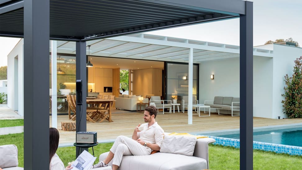 A man sitting under a FlexPatio mororized pergola